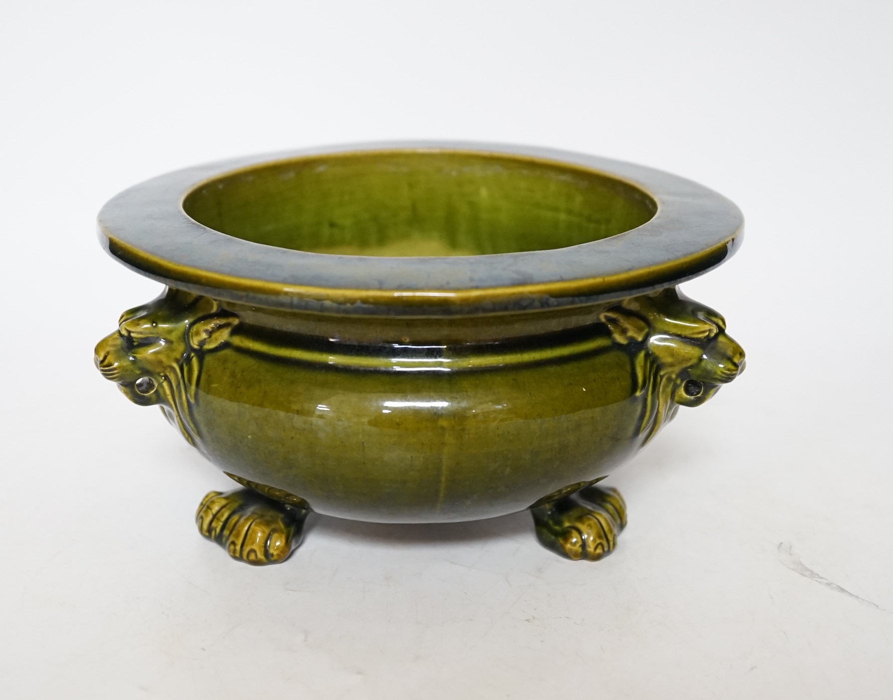A green glazed Art pottery planter raised on three paw feet, diameter 20.5cm